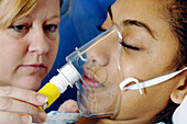 Nurse fitting respiratory mask to patient