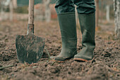 Farmer in rubber boots using spade