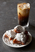 Beignets - deep fried pastry with icing sugar, iced coffee