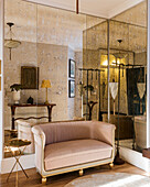 Mirrored wall with vintage French two-seater sofa upholstered in pink velvet
