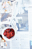 Tomato confit in a small bowl on newspaper