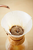 Hot water being poured over coffee in a glass chemex