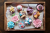 Pretty iced cupcakes on a wooden tray