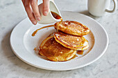 Pancakes with maple syrup being poured