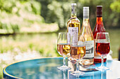 Weingläser und Weinflaschen auf Tisch in der Sonne