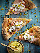 Pizza with cooked ham, burrata and pistachios