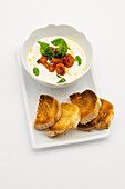 Cream cheese with baked cherry tomatoes and basil served with bread