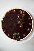 Chocolate tart garnished with currants and stevia leaves