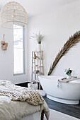Palm frond behind free-standing bathtub in bedroom
