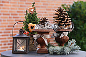 Kiefernzapfen in Rostamphoren, Bäumchen weihnachtlich dekoriert und Laterne