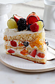 A piece of cream cake with lots of fruit