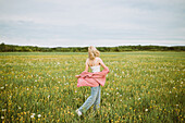 Side view of anonymous female walking along blossoming summer field and enjoying freedom