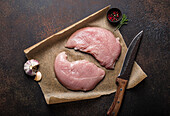 Turkey lean raw fillet on baking paper with rosemary, garlic and spices