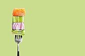 Close-up of fork with food on it: salmon, cucumber, onion, green salad