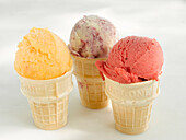 Three cake cones with one scoop of ice cream in each