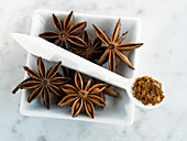 One bowl with star anise and one spoon with ground star anise