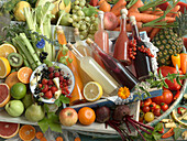 Flaschen mit selbstgemachtem Obstsaft und Gemüsesaft, umgeben von verschiedenen Sorten Obst und Gemüse