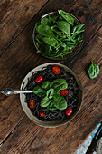Cooked spaghetti with cuttlefish ink arranged with cheese and vegetables