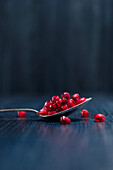 Red fresh juicy pomegranate fruits seeds on spoon and dark wooden surface on blue background