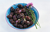 Blue bowl with black olives and chive blossoms