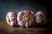 Three purple garlic bulbs on a wooden background
