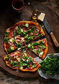 Pizza mit Parmaschinken und Rucola auf Pizzabrett