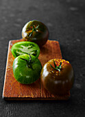 Green and black tomatoes on a wooden board