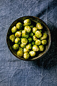Bowl of whole baked brussel sprouts on blue tablecloth. Vegan dish