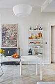 A fruit bowl on a white dining table in front of a string shelf with vintage decorations