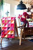 Patchwork blanket on armchair in front of color-matching bouquet of dahlias