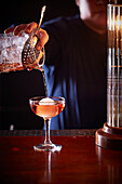 Eleganter Litschi-Cocktail wird auf Bartheke eingeschenkt