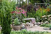 Stone bench with woollen blanket in a colorful perennial garden