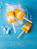 Mango coconut popsicles in a bowl with crushed ice