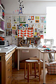 Hocker am Schreibtisch in einer Werkstatt mit Zeichnungen und Drucken an der Wand