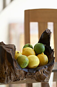 Zitrone und Limetten in geschnitzter Holzschale