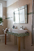 Silver framed mirror above tiled double washbasin in Devon bathroom