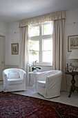 White upholstered armchairs at window of Arundel living room, West Sussex
