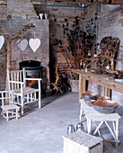 A bare brick walled room with a concrete floor containing rustic furniture and a small stove