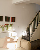 Details of a modern living room with a beige sofa in front of a staircase with a painted wooden banister