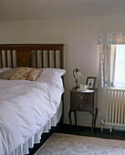 Lamp and cup of tea on a bedside table in a country style bedroom