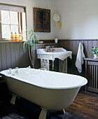 Badezimmer im Landhausstil mit Klauenfuß-Badewanne, verziertem Waschbecken, Holzvertäfelung und Holzboden