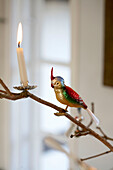 Christmas ornament in shape of parrot and candle on tree branch