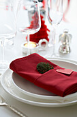 Weihnachtlich gedeckter Tisch mit einem in eine rote Serviette gewickelten Zweig