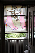Damenfüße mit Stilettos und Slip als Motiv auf geschlossenem Rollo in Londoner Wohnung