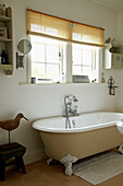 Freistehende Rolltop-Badewanne unter dem Fenster eines Hauses in West Sussex, England, UK