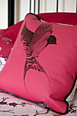 Black bird in flight on pink cushion in Brighton townhouse, Sussex, England, UK