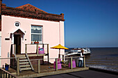 Frau auf der Balkonterrasse eines Strandhauses in Cromer, Norfolk, UK