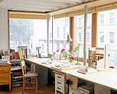 An overview of a home office space with desk in front of a large window that spans the whole room