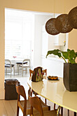 The view looking towards the kitchen past the oval dining table with black lampshades suspended above