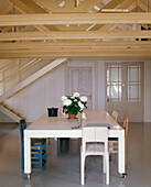 Country style dining room with exposed wooden beams above a contemporary dining table